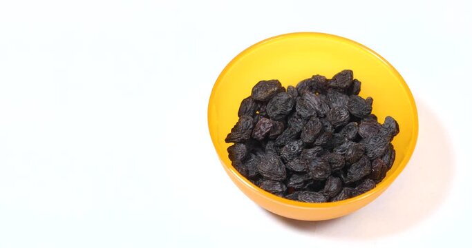 Person picking fresh raisins from yellow bowl, close up