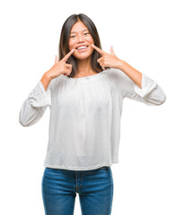 Young asian woman over isolated background smiling confident showing and pointing with fingers teeth and mouth. Health concept.