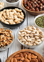 Mixed raw nuts and seeds in bowls on kitchen table.Peanut,hazelnut,walnut,almonds,pistachio,sunflower,pumpkin,chia and cashew.Macro