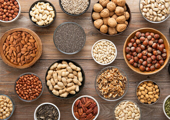 Peanut,hazelnut,walnut,almonds,pistachio,sunflower,pumpkin,chia,pecan and cashew mixed healthy nuts and seeds in various bowls on wooden background.Top view.