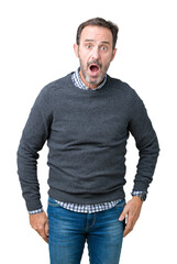 Handsome middle age senior man wearing a sweater over isolated background afraid and shocked with...