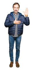 Middle age handsome man wearing winter coat Swearing with hand on chest and open palm, making a...