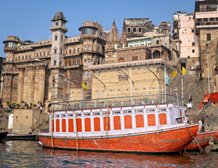 Colorful boat parked in front of Brij Rama Palace-Ancient building on Darbhanga ghat in Varanasi,...