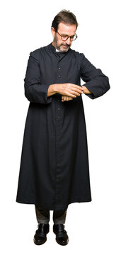 Middle age priest man wearing catholic robe Checking the time on wrist watch, relaxed and confident