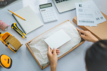 Closeup small business owners online Prepare to package products for delivery to customers according to their orders with a blank white label or business card to write a message.