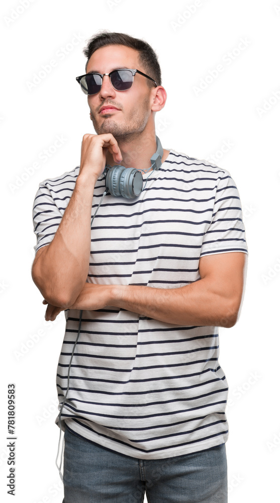 Poster Handsome young man wearing headphones with hand on chin thinking about question, pensive expression. Smiling with thoughtful face. Doubt concept.