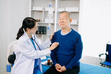 Fototapeta premium Doctor in white suit take notes while discussing and Asian elderly, man patient who lying on bed with receiving saline solution in hospital .