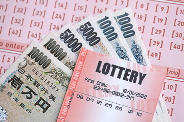 Lottery tickets lies with japanese yen bills on gambling sheets with numbers for marking to play lottery. Lottery playing concept or gambling addiction