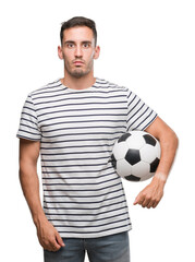 Handsome young man holding soccer football with a confident expression on smart face thinking serious