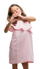 Brunette hispanic girl wearing pink dress smiling in love showing heart symbol and shape with hands. Romantic concept.