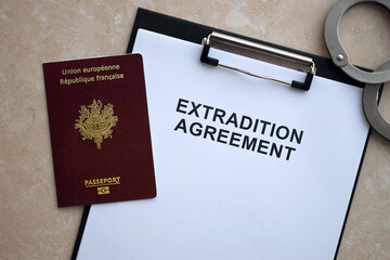 Passport of France and Extradition Agreement with handcuffs on table close up