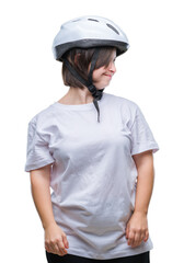 Young adult cyclist woman with down syndrome wearing safety helmet over isolated background looking away to side with smile on face, natural expression. Laughing confident.