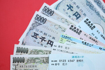 Light blue and red Japan Health Insurance cards on table with japanese residence card and my number card close up