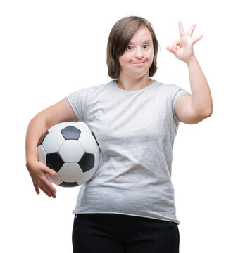 Young adult woman with down syndrome holding soccer football ball over isolated background doing ok sign with fingers, excellent symbol