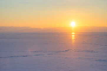 Sunrise over ice-covered Lake Baikal. Beautiful morning winter landscape. The sun rises above the mountains on the horizon. Bright sunlight. Republic of Buryatia, Siberia, Russia. January, winter. - 781818112