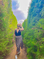 beautiful young woman with sunglasses walking in a tree maze