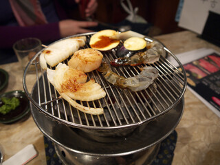 Assorted seafood set with big Hotate scallop and shrimps and vegetables on round Yakiniku grill 