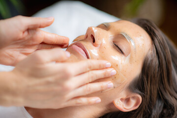 Woman at the beauty salon enjoys a rejuvenating skincare face mask treatment