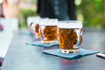 Row of beer glasses on an outdoor table - beer taste refreshing moment under the open sky,...