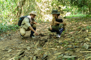 Asian male and female geologist researcher analyzing rocks with a magnifying glass in Mae Wang Nature Park