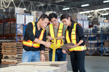 Male and female warehouse workers working and inspecting product on load cart in the storage warehouse. Group of warehouse workers moving products in distribution branch