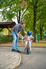 Family father teaches child daughter to ride public bike on one of traffic playground in Prague, Czech republic