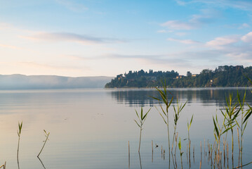 Sunrise on a lake in northern Italy. Lake Varese seen from Gavirate towards Biandronno. Frequented for fishing, rowing, walking and cycling along the 28 km cycle path around the lake