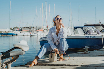 Woman in white shirt in marina , surrounded by several other boats. The marina is filled with boats...