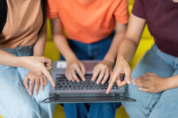 Closeup shot of fingers of group of 3 Asian female students pointing at laptop screen doing...