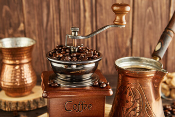 Vintage coffee grinder, cezve for brewing coffee and copper cup on wooden background