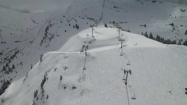 Busy ski resort in the Alps, chairlifts and skiers, 4K drone shot