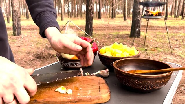 Close up Chopping garlic on a cutting board for a campfire dish. Outdoors cooking. High quality FullHD footage