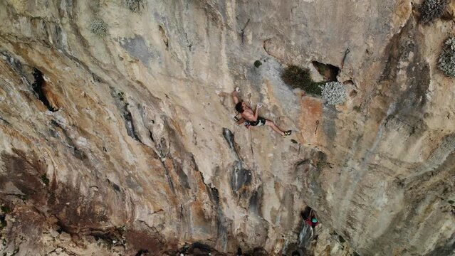 Strong climber climbing a difficult sport climb route in a steep wall at Kalymnos island, Greece. High quality 4k footage.