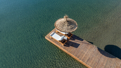 Empty deck sun bed with comfy mattresses on a wooden pier by the tranquil Mediterranean Sea....
