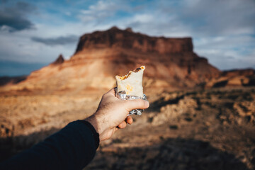 Holding a burrito in front of a butte in the desert