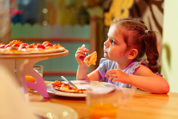 Little Girl Sitting at Table Eating Pizza