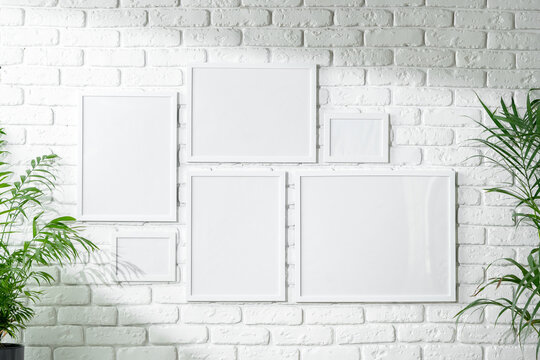 Varied Sized Photo Frames Displayed on a White Brick Wall