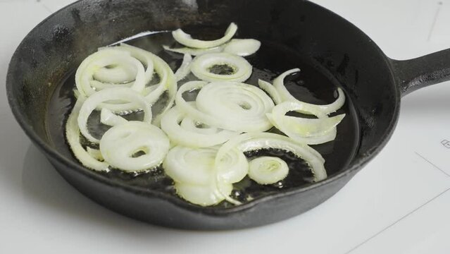 The video depicts onions sautéing in a heated skillet, filling the kitchen with aroma. Ideal for culinary recipe videos and food product advertisements