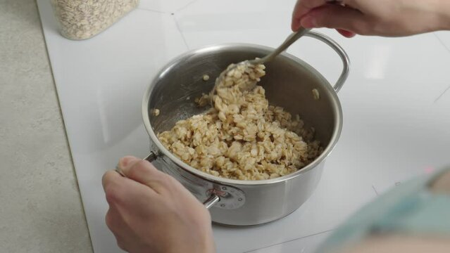 The video shows oatmeal cooking in a saucepan, demonstrating the process of preparing a healthy breakfast. Suitable for culinary clips and promoting a healthy lifestyle