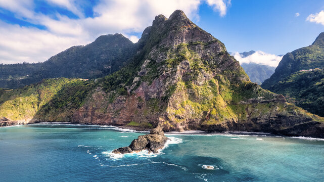 Breathtaking Madeira panorama - powerful cliffs, surging sea, foamy cascades, and lazy clouds. The contrast of raw nature with the blue sky amazes nature lovers