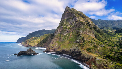 Breathtaking Madeira panorama - powerful cliffs, surging sea, foamy cascades, and lazy clouds. The contrast of raw nature with the blue sky amazes nature lovers