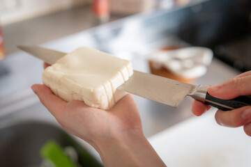 Woman cutting tofu with a knife in japan