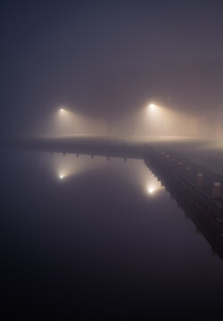 A suburb and streetlights at the waterfront in the dense fog.