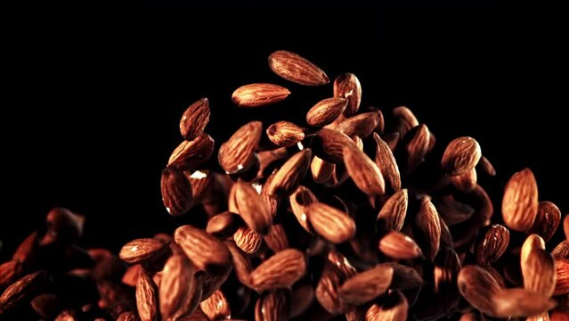 Mesmerizing macro photography capturing a pile of almonds falling dramatically on a dark background, creating a visually stunning image