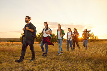 Group of young people on a hiking tour out of town. Happy healthy male and female tourists with...
