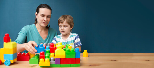 mother and child son  playing with lots of colorful plastic blocks constructor indoor.  The happy family spends time together at home. banner. copy space