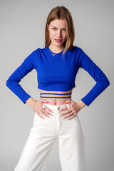 Young Woman model in Blue Top and White Pants posing on white background
