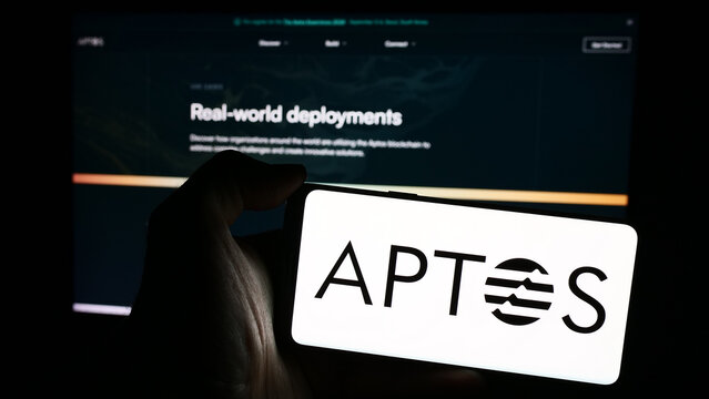Stuttgart, Germany - 03-28-2024: Person holding mobile phone with logo of protocol development organisation Aptos Foundation in front of web page. Focus on phone display.