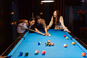 Young diversity group of people playing pool together with smile, enjoyment and fun. Young people...