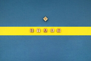 STARTの英語ブロックをのせた青い背景の黄色いスタートライン